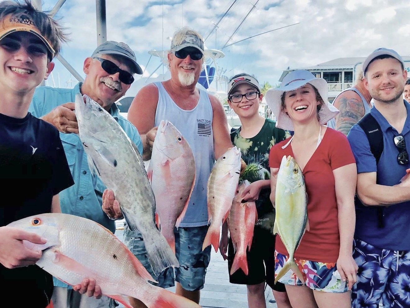 a group of people standing next to a person holding a fish